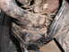 1985 GMC Jimmy - Close-up view of heavily corroded vehicle suspension components, obscured by dirt and debris.
