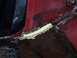 1978 Ford Bronco - Seam sealer is applied to a section of a red vehicle's bodywork.