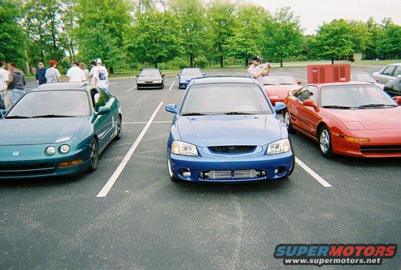 Blue sedan with aftermarket intercooler parked in a lot, front view