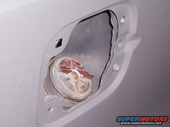 Gray vehicle's open fuel filler door revealing a metal cap with red and white markings