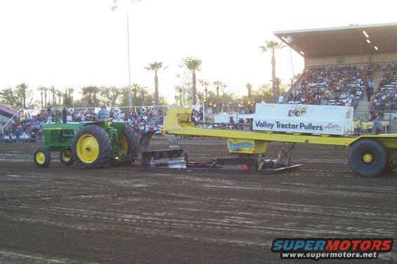Green tractor pulling weighted sled at tractor pull event