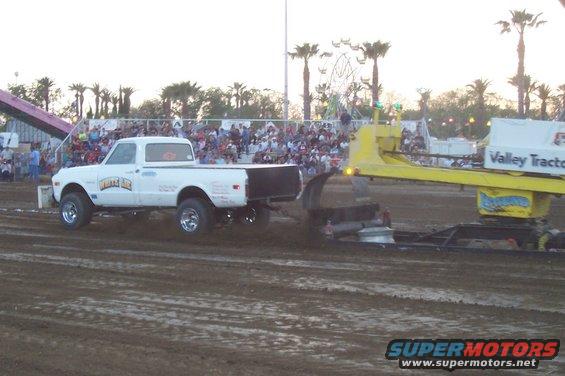 White 1972 Chevrolet C10 pickup truck with "White Lie" text on door, pulling a sled in a dirt track event