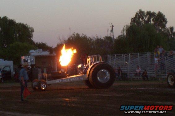 Dragster with flames erupting from exhaust, side view. Text on side reads "White Lightning"