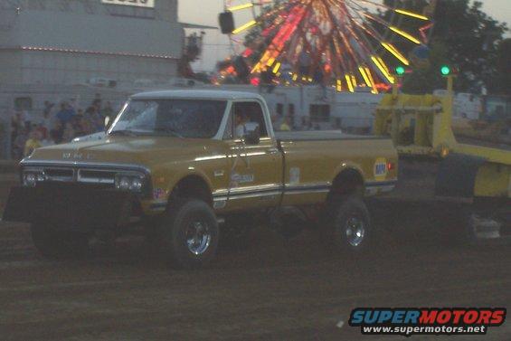 Yellow 1971 GMC pickup truck with a white roof, lifted suspension, and a plow attachment