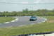 1993 Ford Mustang - A blue Ford Mustang navigates a turn on a race track during a sunny day.