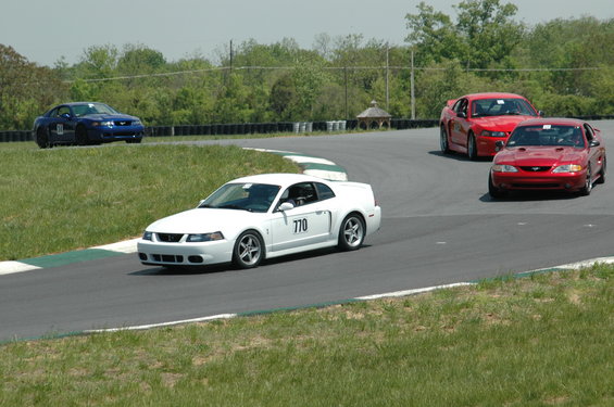 White Mustang with number 770 on door, racing with two red Mustangs on a track