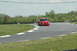 1993 Ford Mustang - A red pickup truck navigates a turn on a race track during the daytime.