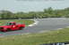 1993 Ford Mustang - A red pickup truck drives around a corner on a race track with green grass and trees in the background.
