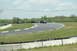 1993 Ford Mustang - Multiple cars are seen on a race track during a sunny day with a cloudy sky.