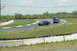 1993 Ford Mustang - A black 1993 Ford Mustang navigates a turn on a race track, with other vehicles in the background.