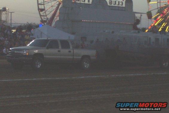 Silver pickup truck with crew cab and long bed at a fairground