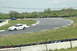 1993 Ford Mustang - A white coupe with a GT-40 decal drives on a race track, with other vehicles in the background.