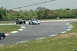 1993 Ford Mustang - A white Ford Mustang with black racing stripes navigates a turn on a race track, with another Mustang visible behind it.