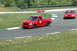 1993 Ford Mustang - A red pickup truck navigates a turn on a race track, with two other red vehicles visible in the distance.