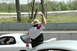 1993 Ford Mustang - A man in a hat and a colorful shirt stands between two white cars, raising his hand on a race track.
