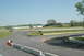 1993 Ford Mustang - A view of a race track with several cars visible in the distance and buildings in the background.