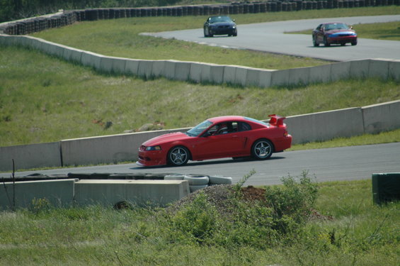 Red sports car with a rear spoiler on a race track, viewed from the front-right