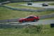 1993 Ford Mustang - A red sports car navigates a turn on a race track, with other vehicles in the background.