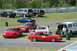 1993 Ford Mustang - A red coupe with racing number 65 is parked on the track, with several other vehicles and people in the background.