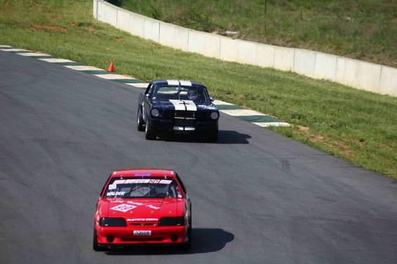 Red 1993 Ford Mustang race car with white racing stripes and number 50 on the windshield, viewed from the front