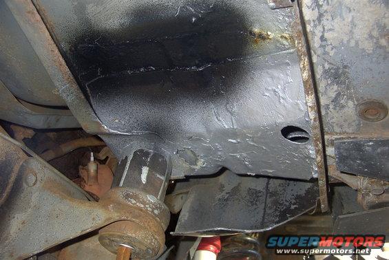 Underside of a vehicle showing frame and suspension components, some parts appear to have been painted