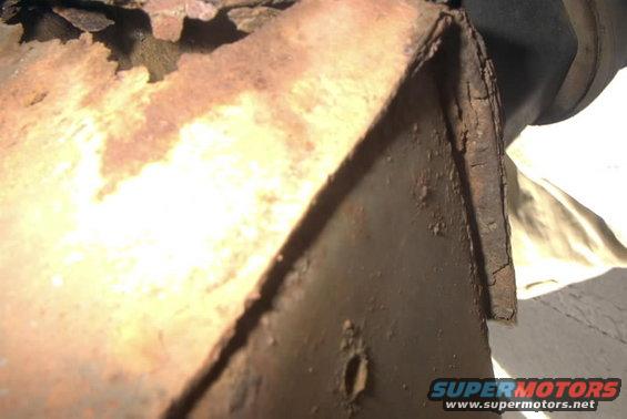 Close-up of rusted metal frame with Supermotors.net logo