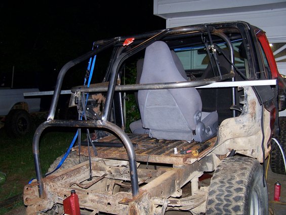 Custom off-road vehicle with roll cage, exposed frame, and bucket seats, viewed from the rear