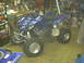 2003 Yamaha RAPTOR 660 - Blue Yamaha Raptor 660 ATV parked in a garage with tools and equipment in the background.