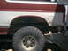 1986 Ford Bronco - Close-up of the rear wheel well and lower body panel of an SUV, showing off-road tires.
