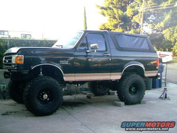 Black Ford Bronco with tan trim, lifted suspension, and large tires, viewed from the front 3/4 angle