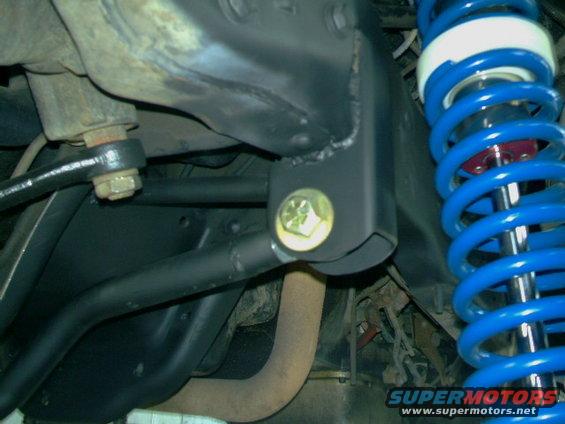 Close-up of blue coilover shock and black suspension bracket with yellow bolt