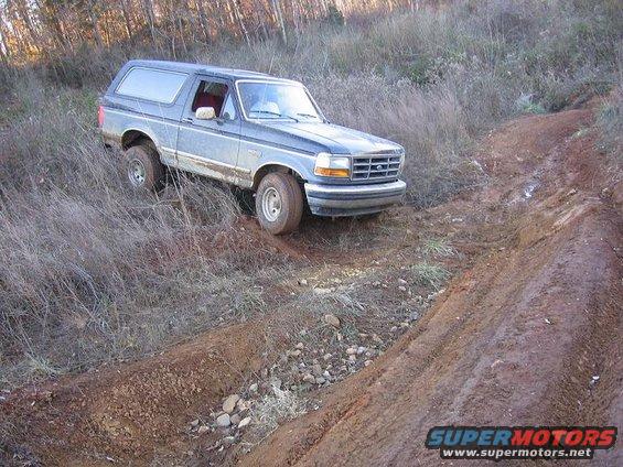 Ford Bronco driving on a muddy trail, front end visible