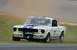 1965 Ford Mustang - A 1965 Ford Mustang race car with blue stripes navigates a turn on a track.