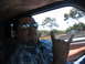 1980 Ford Bronco - A man wearing aviator sunglasses makes a rock-on hand gesture from inside a vehicle, with traffic visible outside the window.