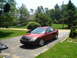 2001 Ford Taurus - Red 2001 Ford Taurus with a car bra on the front parked in a driveway on a sunny day.