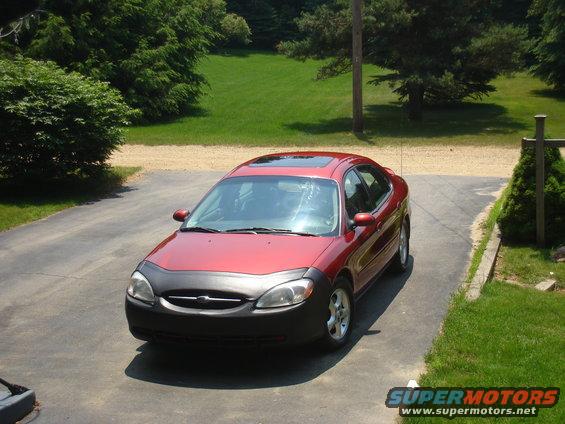 Red sedan with black bug deflector parked on driveway