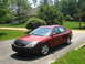 2001 Ford Taurus - A red 2001 Ford Taurus is parked on a driveway in front of a house and trees.