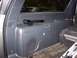 2002 Chevrolet Suburban - A flashlight rests on the storage compartment inside a vehicle, with another car visible outside.