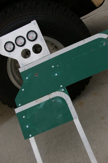 Custom gauge panel with three gauges mounted in front of a vehicle tire and wheel