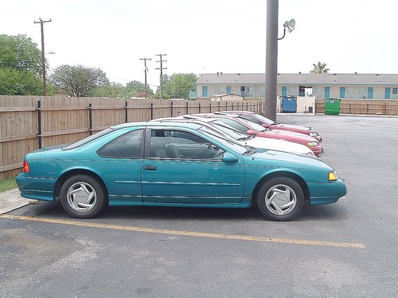Teal Ford Thunderbird coupe parked in a lot, other cars behind it