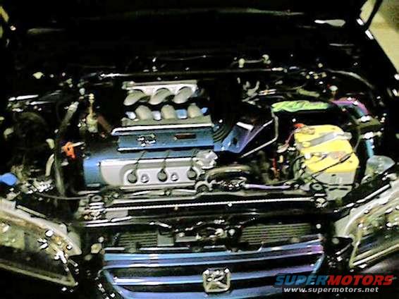 Engine bay with a blue engine cover, yellow battery, and chrome accents
