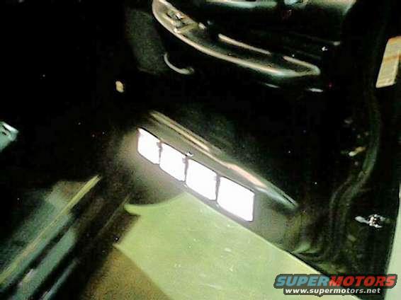 Car interior showing four illuminated square vents on the dashboard