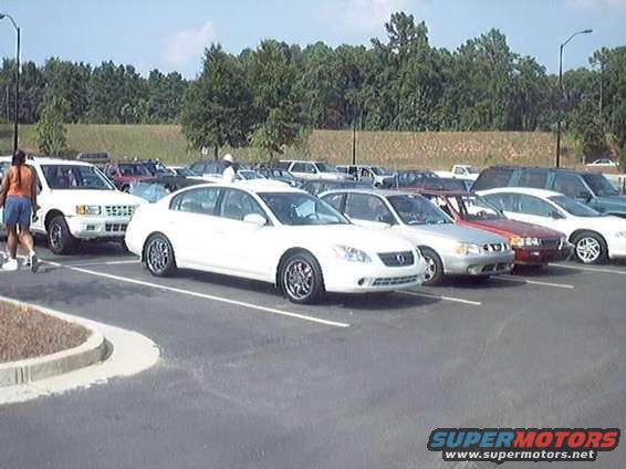 Parking lot scene with a person walking past several cars parked in rows