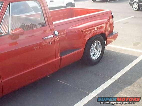 red pickup truck parked in a lot, side view