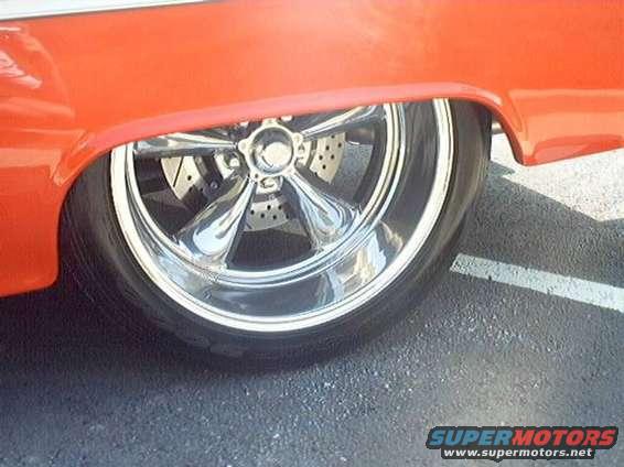 Close-up of a custom chrome five-spoke wheel with drilled brake rotors on an orange vehicle