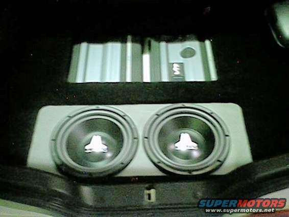 Car trunk interior with two JL Audio subwoofers in a box and two amplifiers mounted above