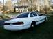 1996 Ford Crown Victoria - White 1996 Ford Crown Victoria sedan seen from the rear quarter angle, parked on a grassy lawn.