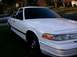 1996 Ford Crown Victoria - A white sedan is parked on a grassy area with another car in the background.