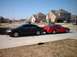 2000 Ford Taurus - A black sedan is parked next to a red coupe on a sunny day in a residential area.