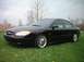 2000 Ford Taurus - A black 2000 Ford Taurus sedan is shown from a three-quarter front view, parked on a grassy area with trees in the background.